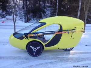 Foto des Arcus-Velomobils mit an der Seite zum Transport festgeschnallten Skiern