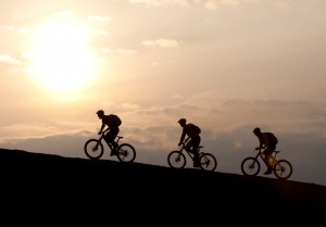 Drei Radfahrer fahren im Gegenlicht einen Berg hinauf
