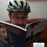 Mann mit Fahrradhelm liest begeistert ein Buch