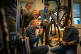 Männer umstehen ein Fahrrad auf einem Montageständer