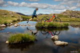 Mann springt über Wasser zu einem Mountainbike