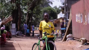 Eine Frau in einem gelbem T-Shirt hält ein grünes Fahrrad.