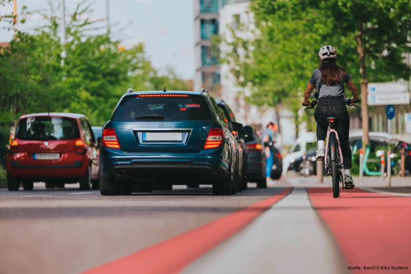 Eine Frau fährt auf einem gut ausgebauten radweg in der Stadt.